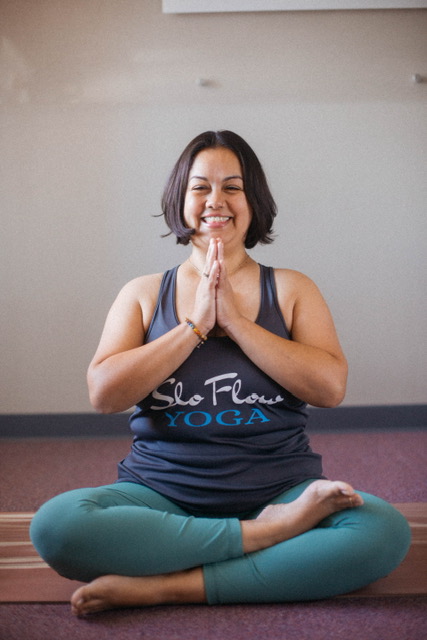 Om Reset instructor sara rosa seated with hand in prayer position.
